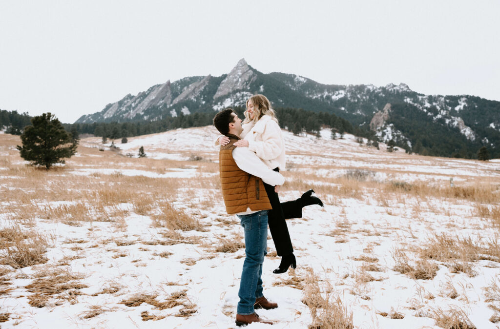 couple posing for engagement photos in the snow and backed my mountain scenery