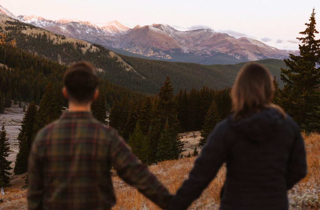 Couple holding hands looking at mountains in Breckenridge