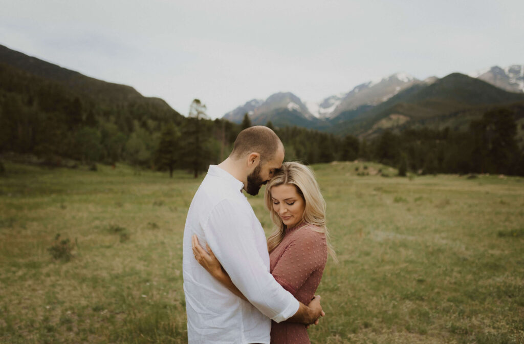 Couple hugging backed by mountains at Rocky Mountain National Park