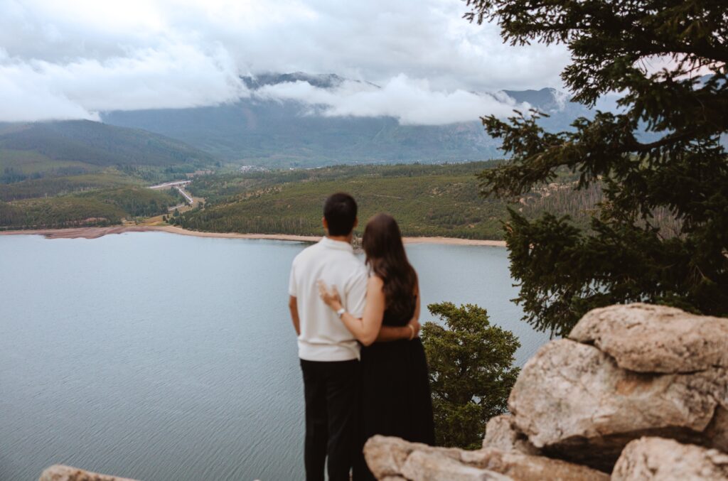 Couple looking at lake and mountains for proposal photos in Colorado