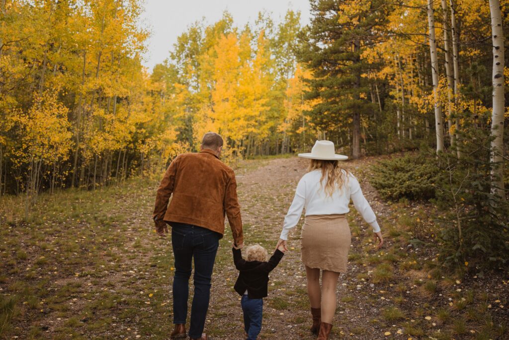 mom and dad holding son's hands for family photos near Denver