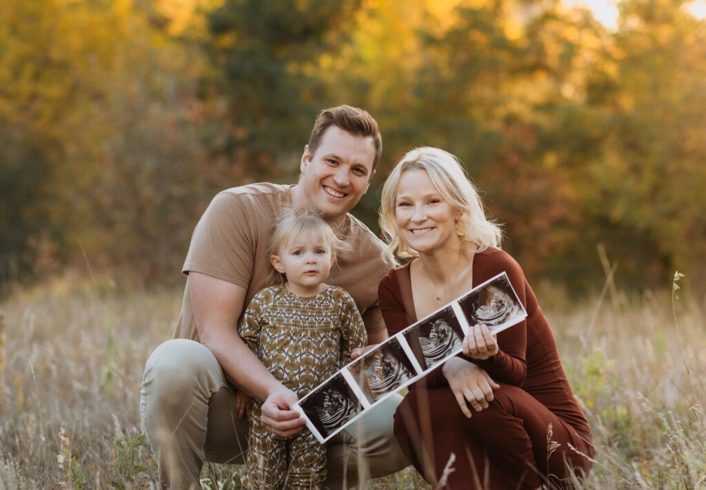 Mom, dad, and daughter with ultra sound pictures posing for family and maternity photos