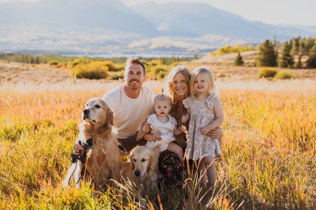 family and dogs taking family photos surrounded by mountain scenery