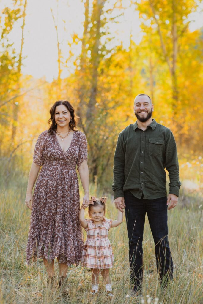 Mom, dad, and daughter posing for family photos in Denver surrounded by trees