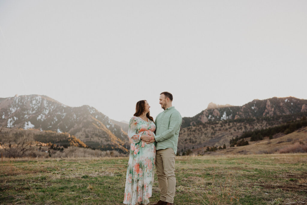 Couple posing for maternity photos smiling at each other
