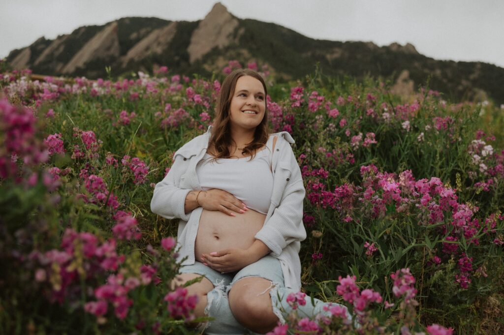 Pregnant mom posing for maternity photos in Denver surrounded by pink flowers