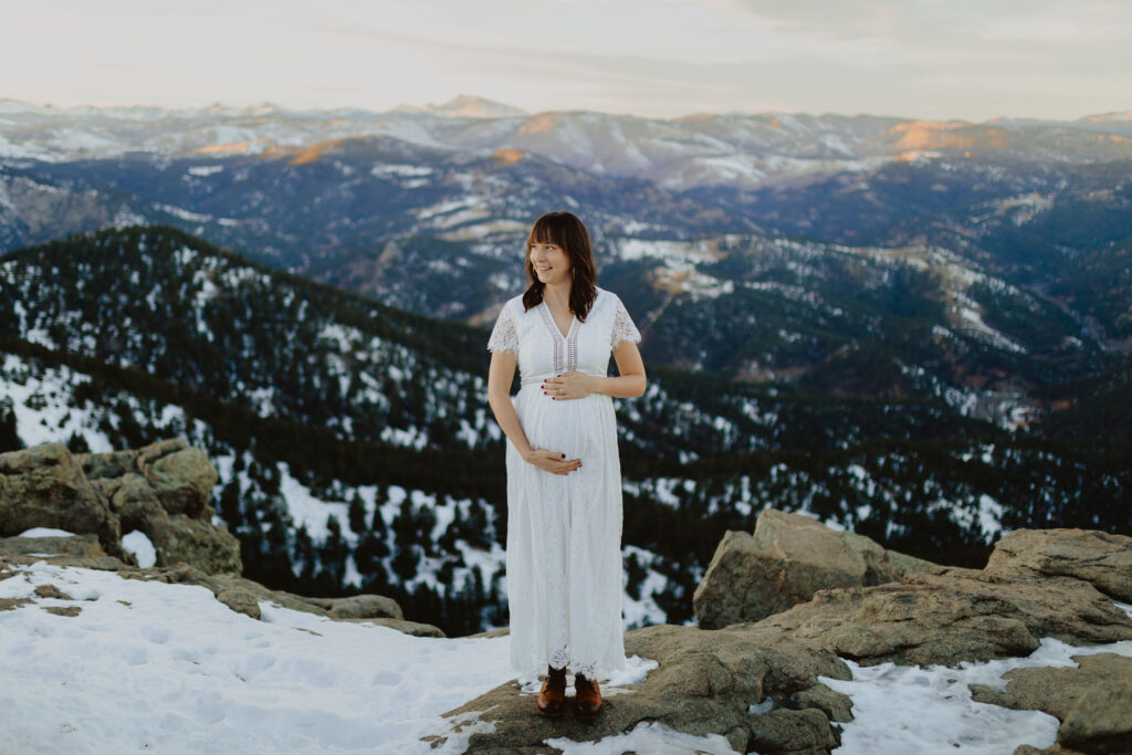 Pregnant mom posing for maternity photos in Denver surrounded by snowy mountains