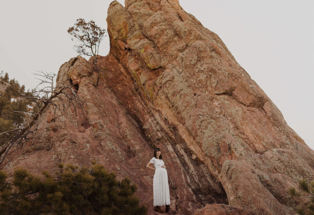 Mom posing for maternity photos in front of red rock formation
