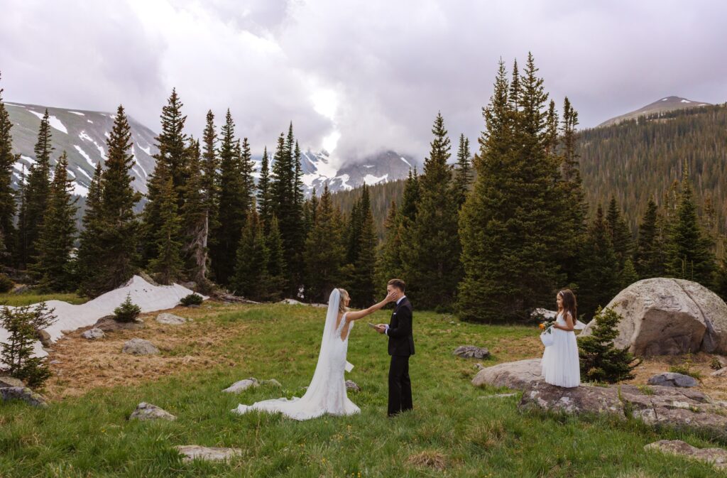 Bride, groom, and daughter at wedding ceremony in Colorado surrounded by trees and mountains