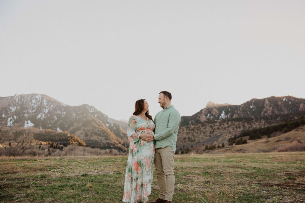 Couple posing for maternity photos backed by mountains