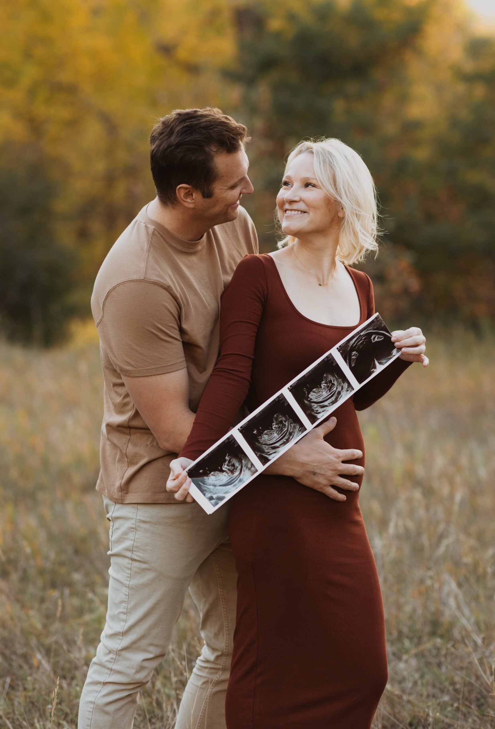 couple posing for maternity photos and mom holding ultra sound pictures