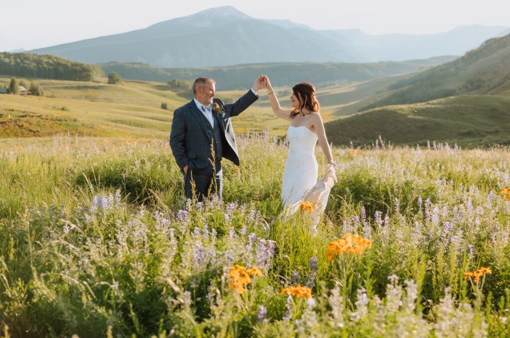 Bride and groom surrounded by flowers and mountain scenery in Crested Butte