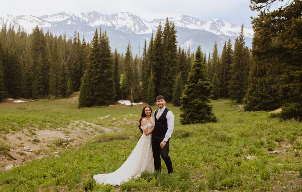 bride and groom standing in front of aspen trees and smiling at camera