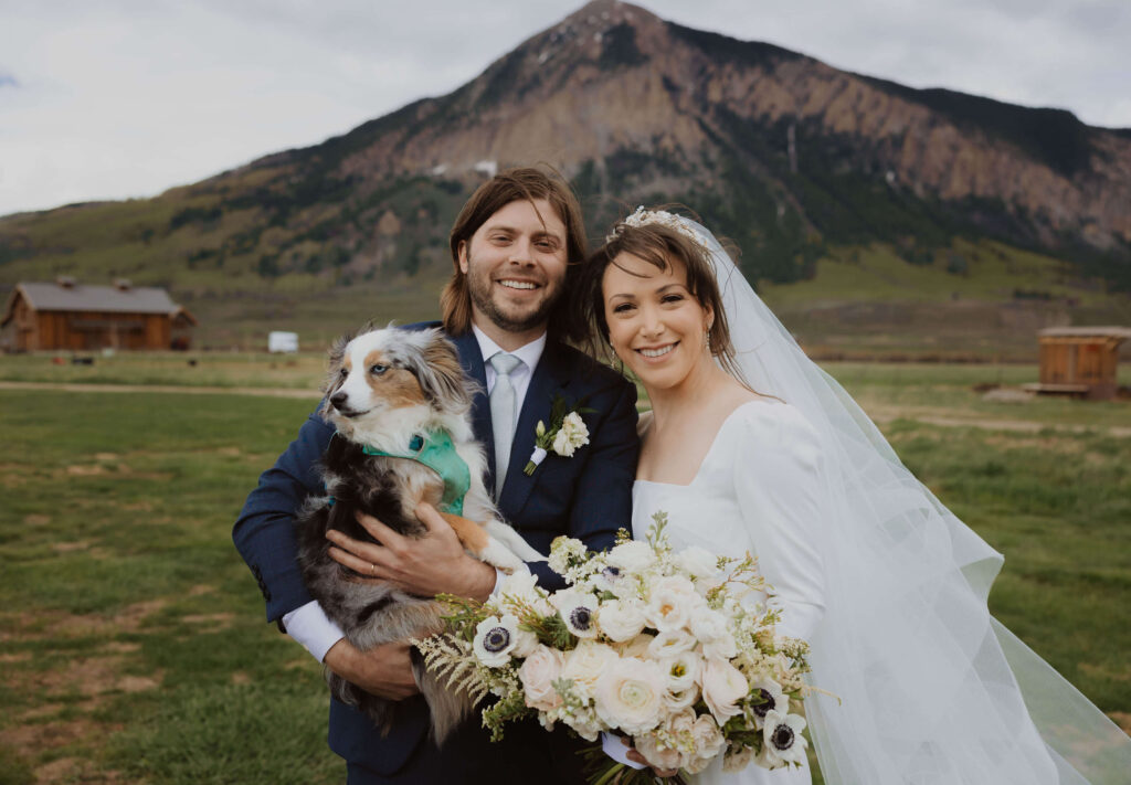 Bride, groom, and dog posing for wedding photo