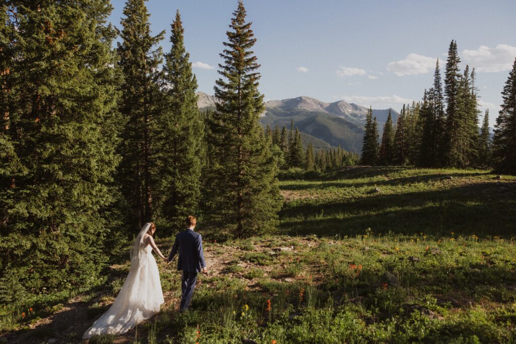 Bride and groom holding hands and walking surrounded by aspen trees