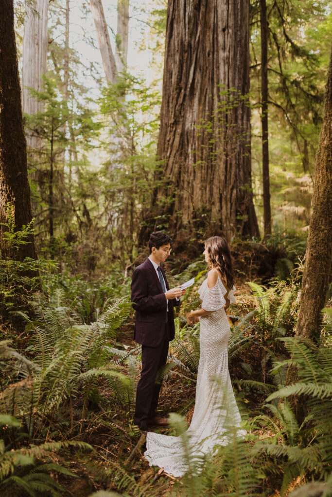 Groom reading vows to bride surrounded by trees