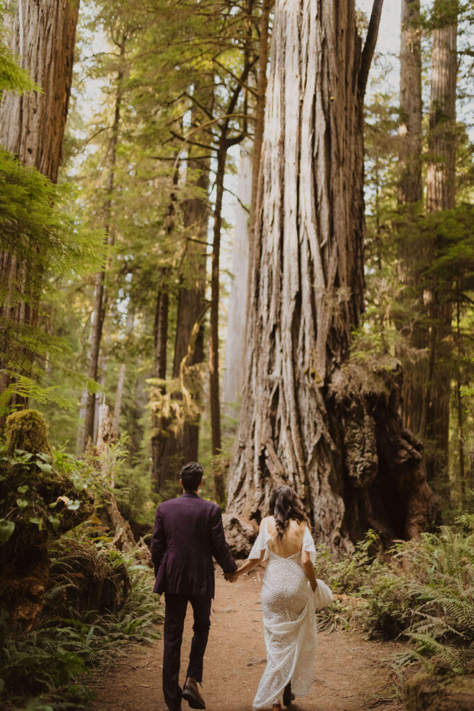 bride and groom in a forest with backs facing camera
