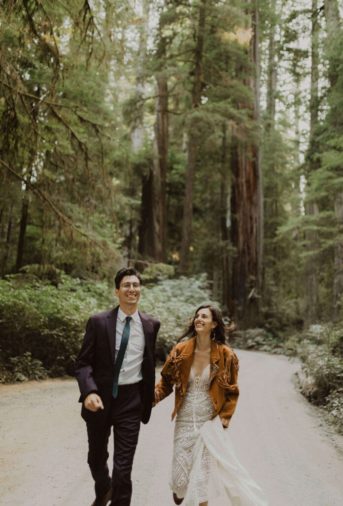 Bride and groom walking on road surrounded by trees
