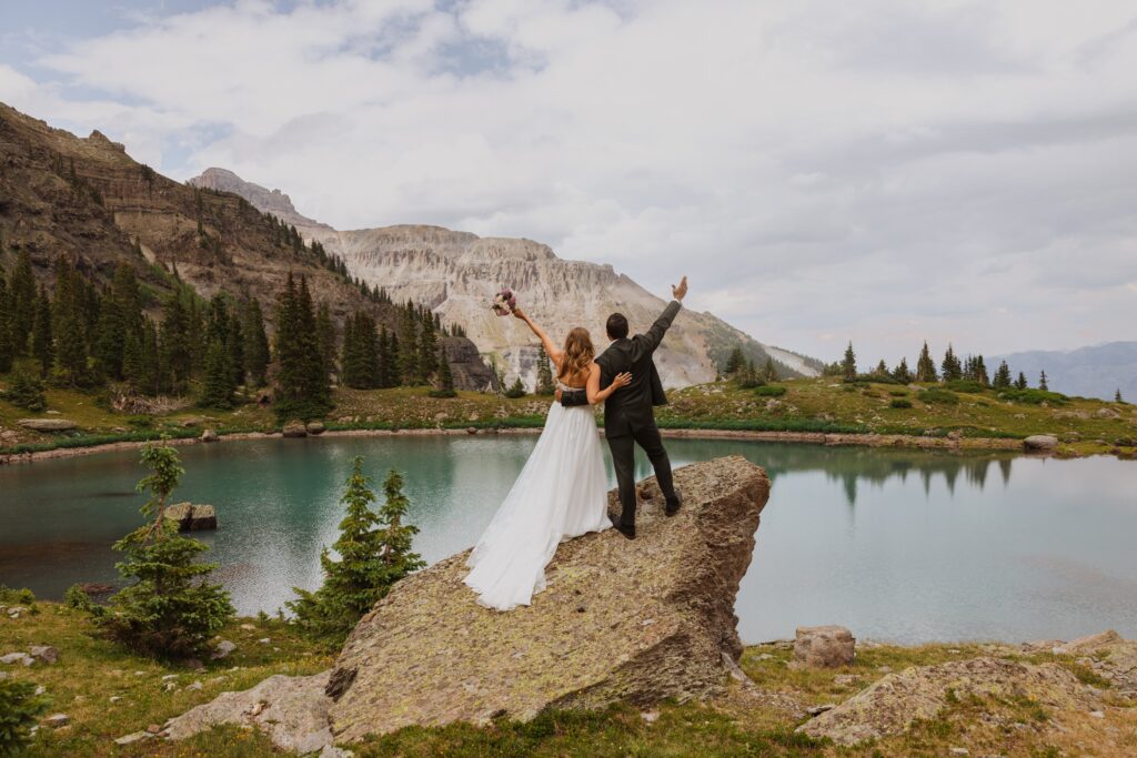 bride and groom facing lake posing for wedding photos