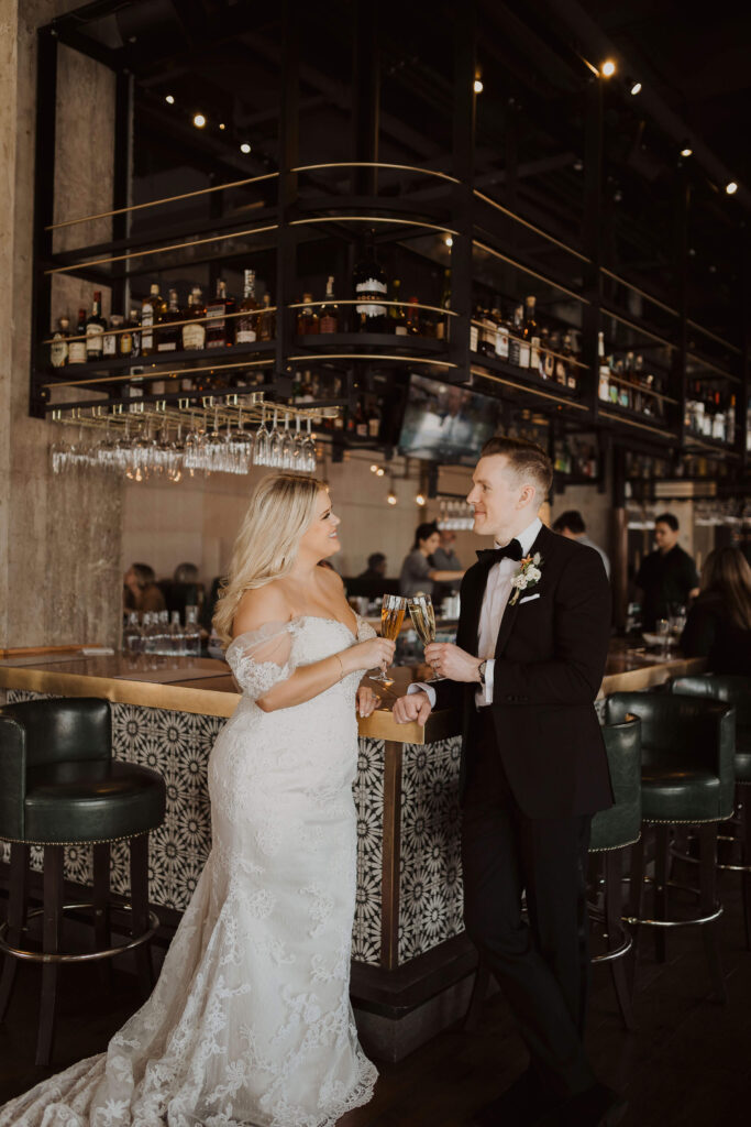 Bride and groom holding champagne at bar for Kansas City elopement