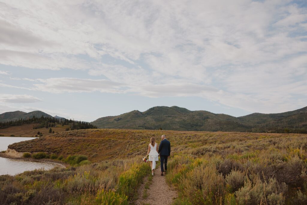 Bride and groom walking next to lake at Bella Vista Estate in Steamboat Springs