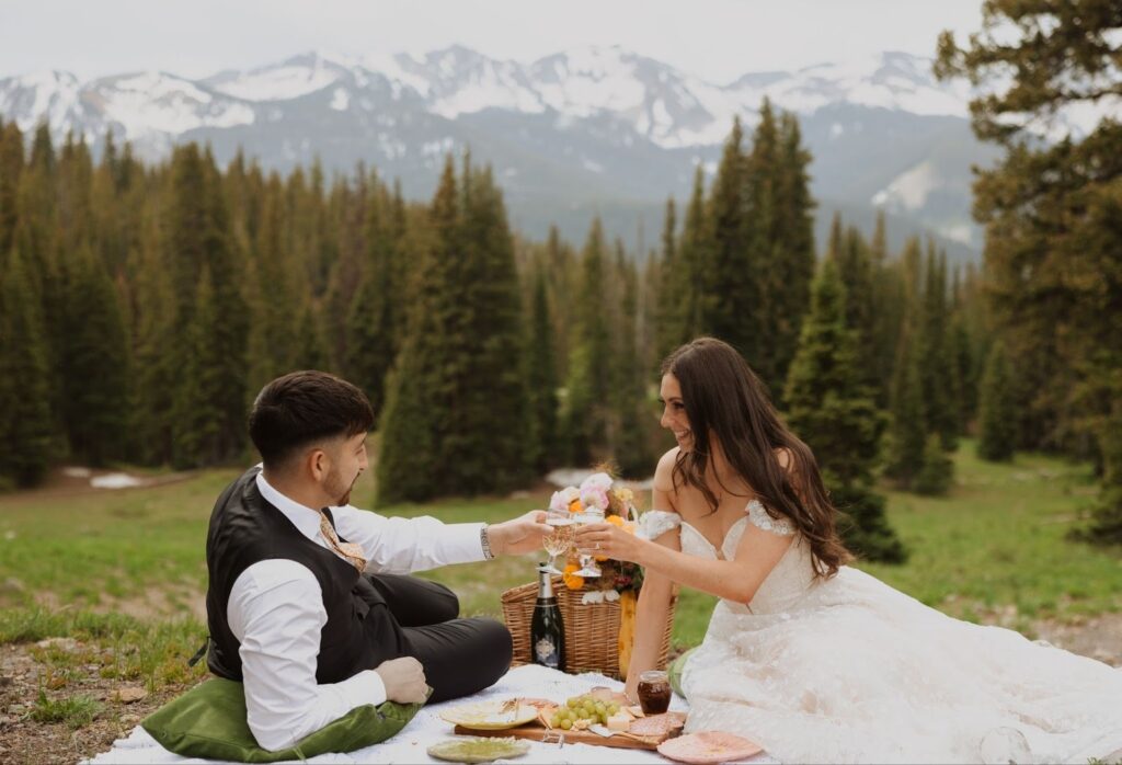 Bride and groom having picnic surrounded by trees and mountains