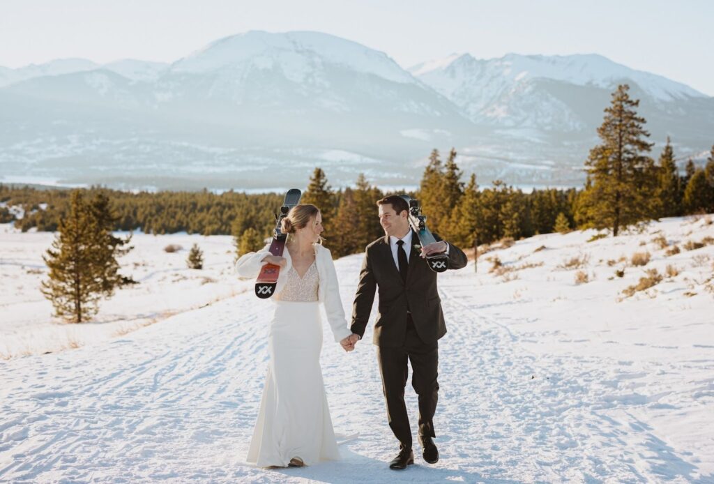 Bride and groom holding hands surrounded by snow and trees