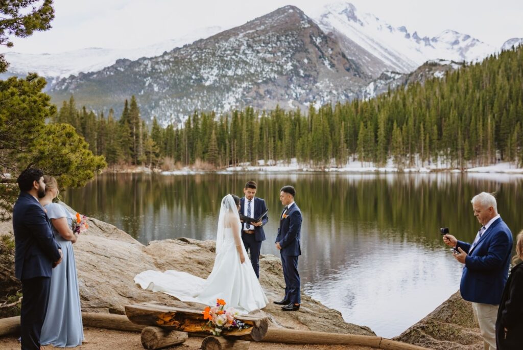 Elopement ceremony with couple and 3 guests backed by lake and mountains