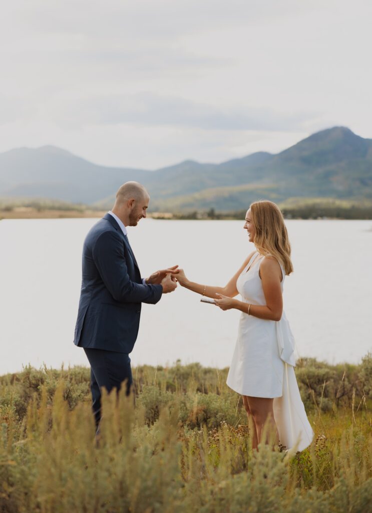 Couple exchanging rings backed by lake and mountains for Steamboat Springs elopement