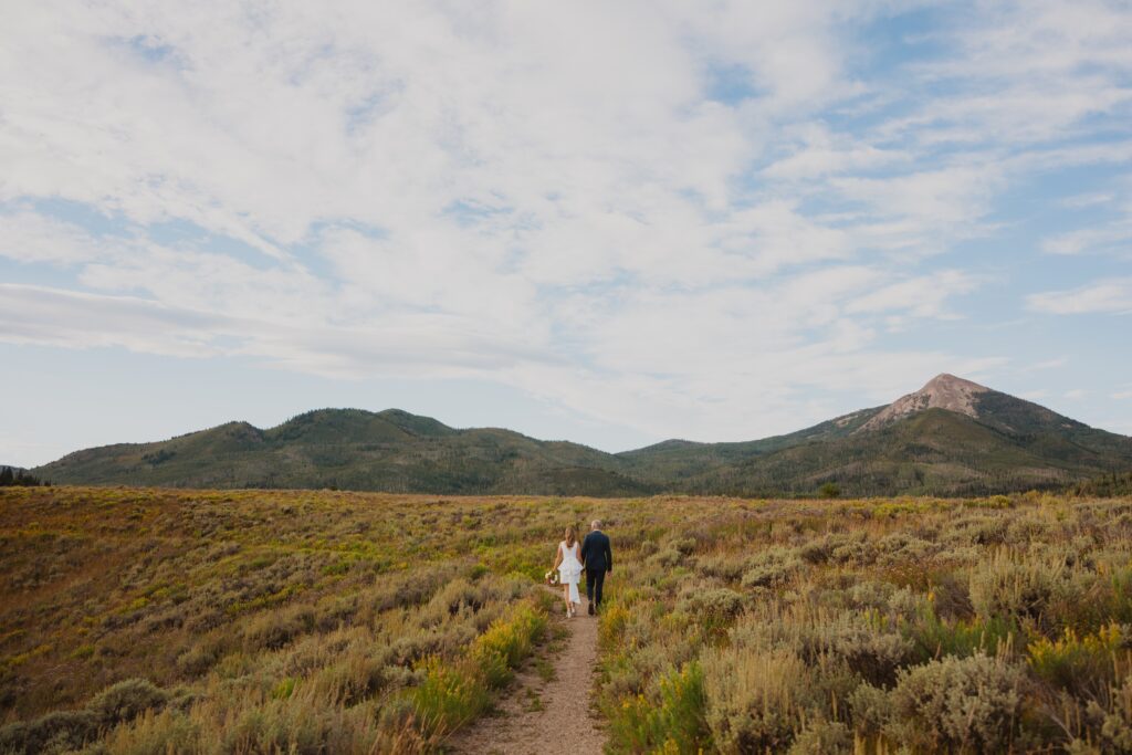 Bride and groom walking towards mountain