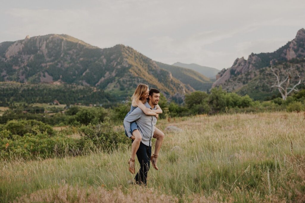 Woman on man's back surrounded by mountains for couples photography in Denver