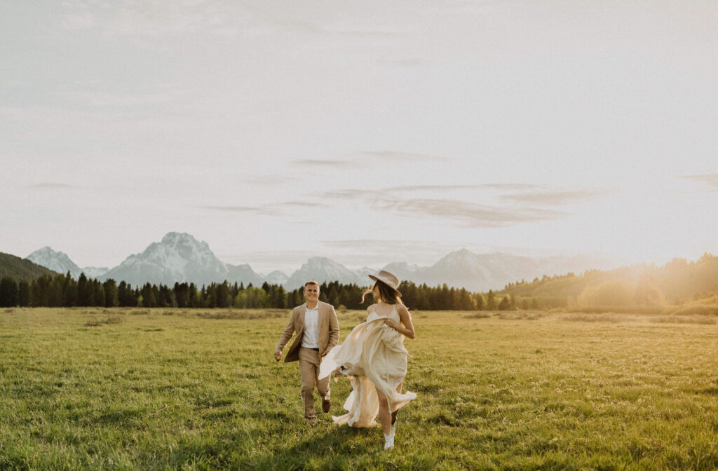 Bride and groom running in field at Grand Teton National Park