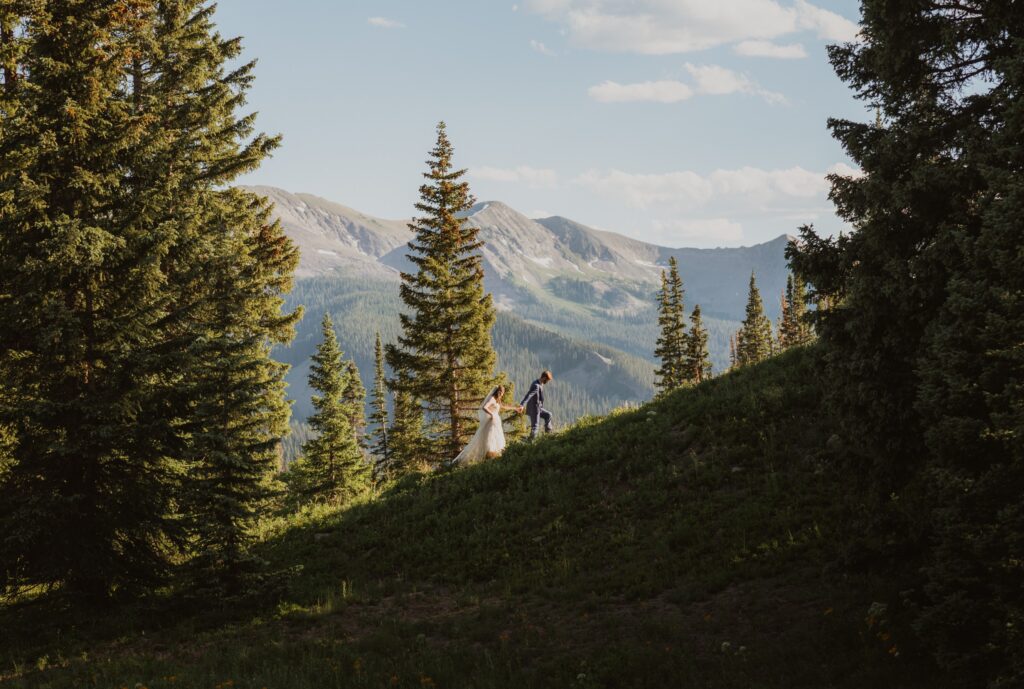 Bride and groom walking around trees and mountains for elopement