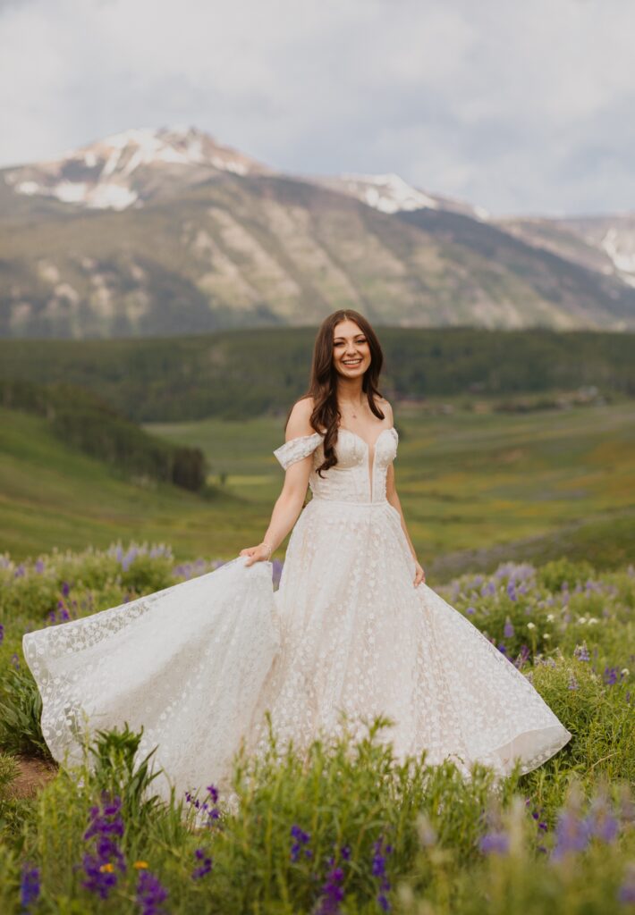 Bride smiling at camera surrounded by beautiful purple flowers