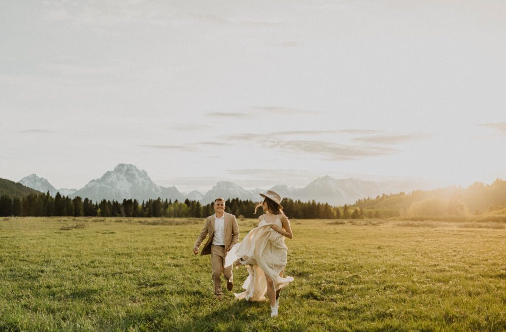 Couple running in field at Grand Teton National Park