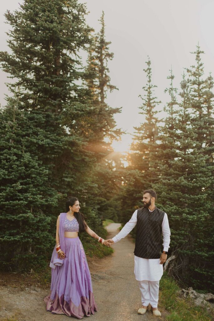 Bride and groom holding hands and smiling at each other surrounded by aspen trees