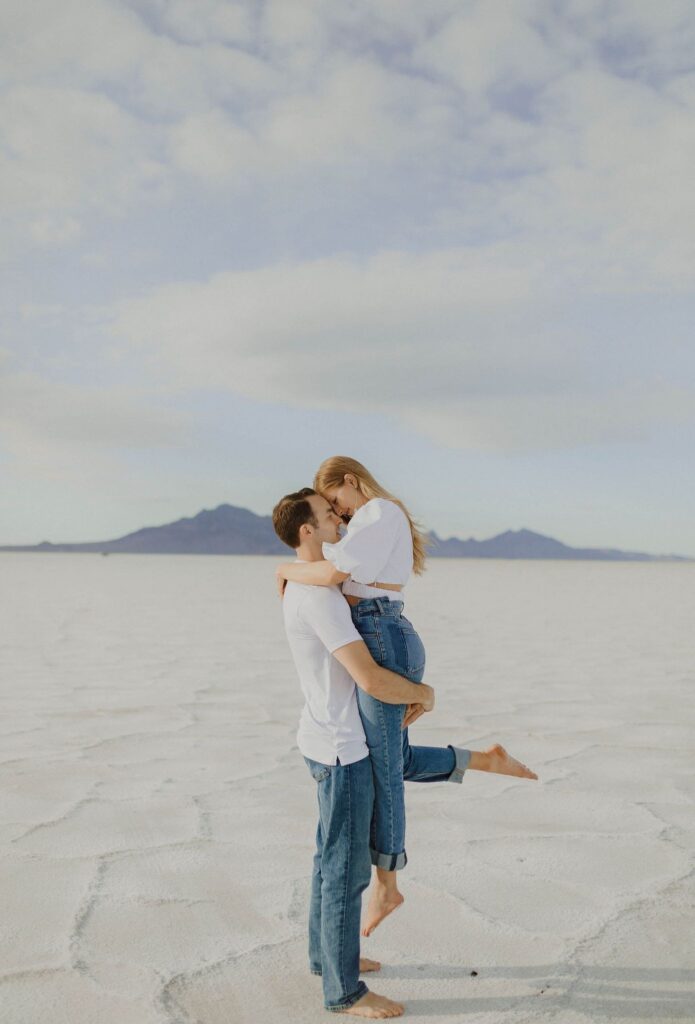 Man holding woman up surrounded by salt flats in Utah