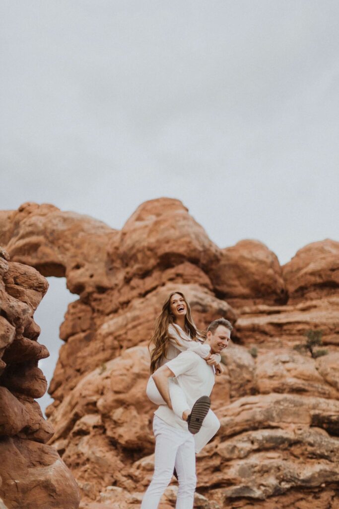 Couple laughing surrounded by red rock formations at Arches National Park