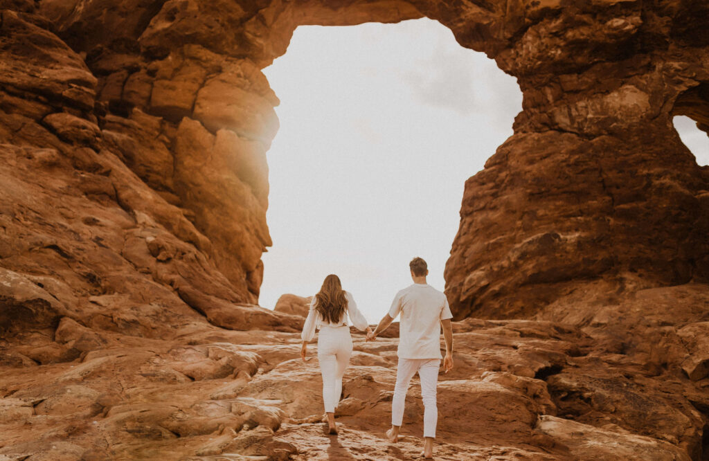 Couple walking at Arches National Park surrounded by red rock formations