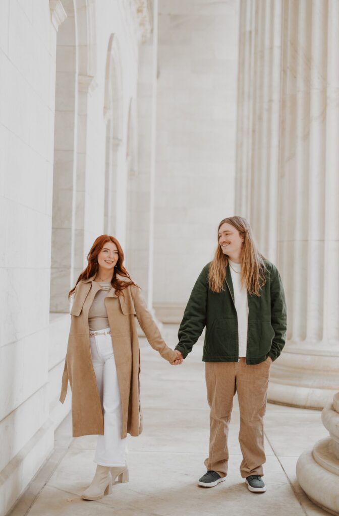 Couple holding hands and smiling in front of building in Downtown Denver