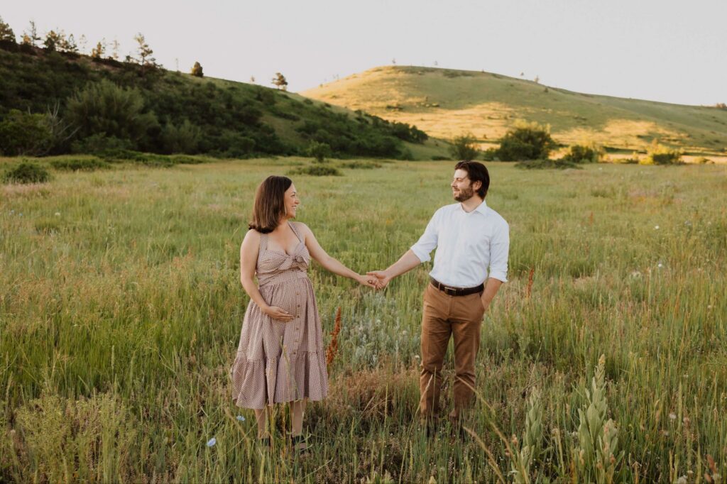 Man and pregnant woman posing in field for maternity photos in Kansas City