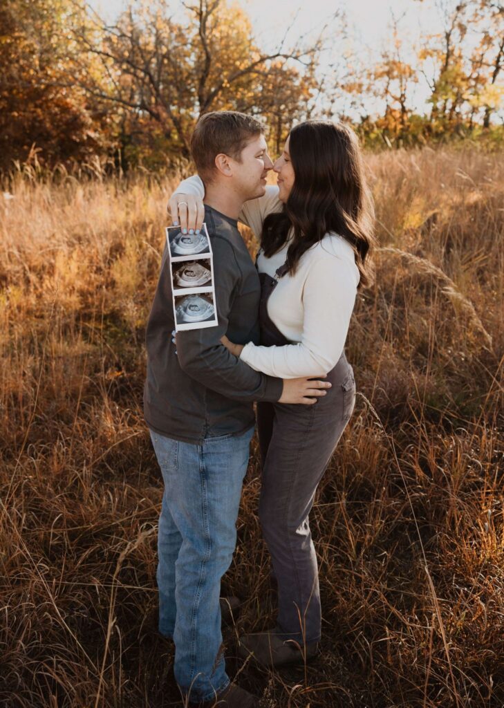 Man and woman holding sonogram for maternity photos in Kansas