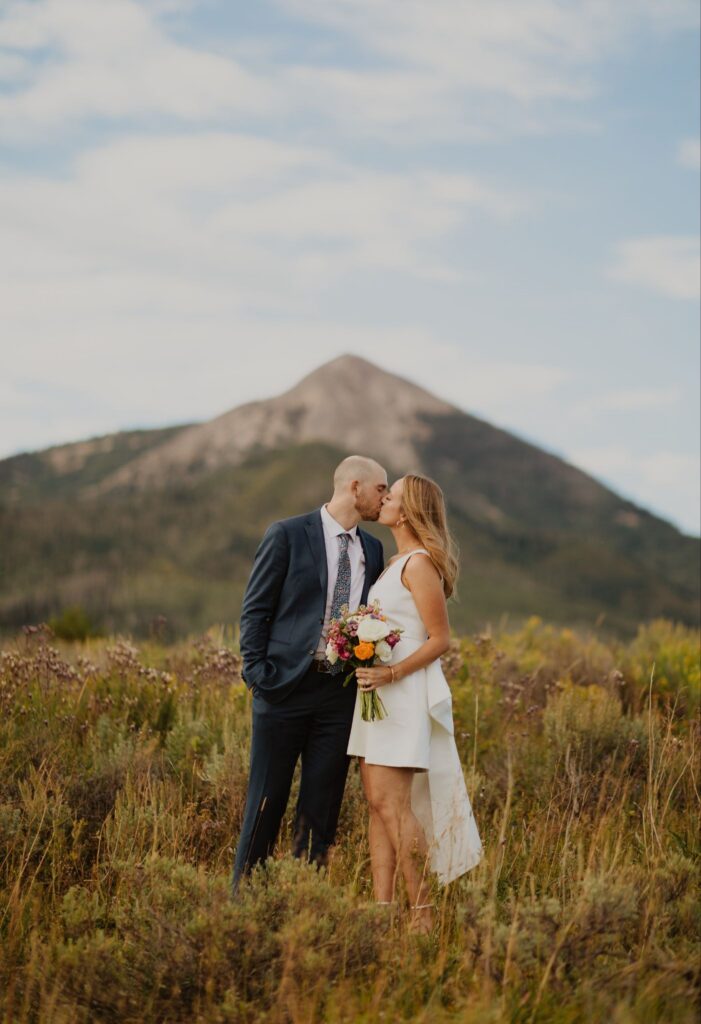 Bride and groom share a kiss in front of a mountain in a Steamboat Springs wedding