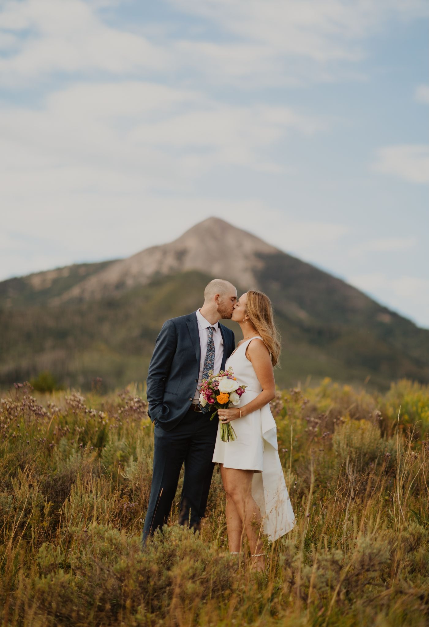 Bride and groom share a kiss in front of a mountain in a Steamboat Springs wedding