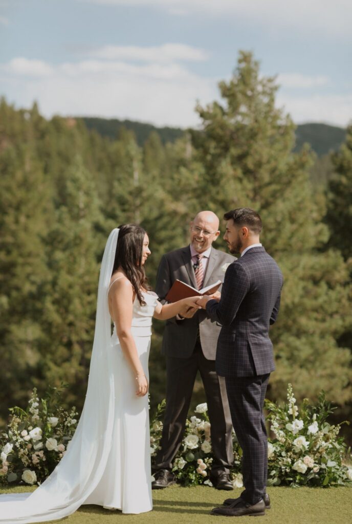 Bride and groom during wedding ceremony surrounded by pine trees