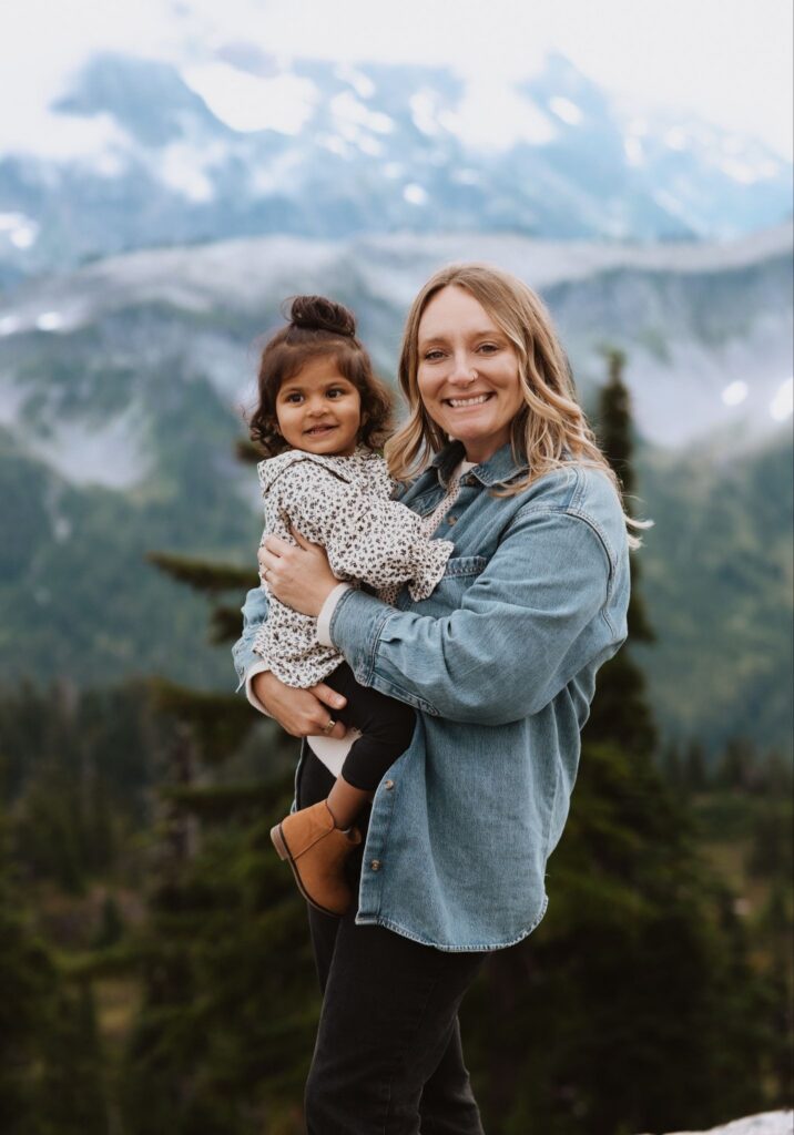 Maternity photographer holding baby and smiling at camera