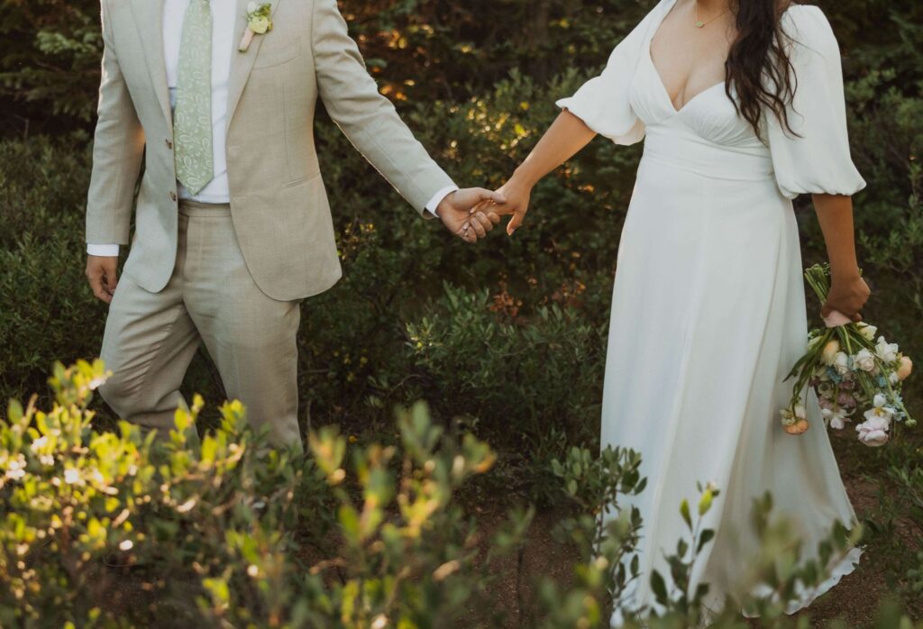 Bride and groom walking holding hands in garden