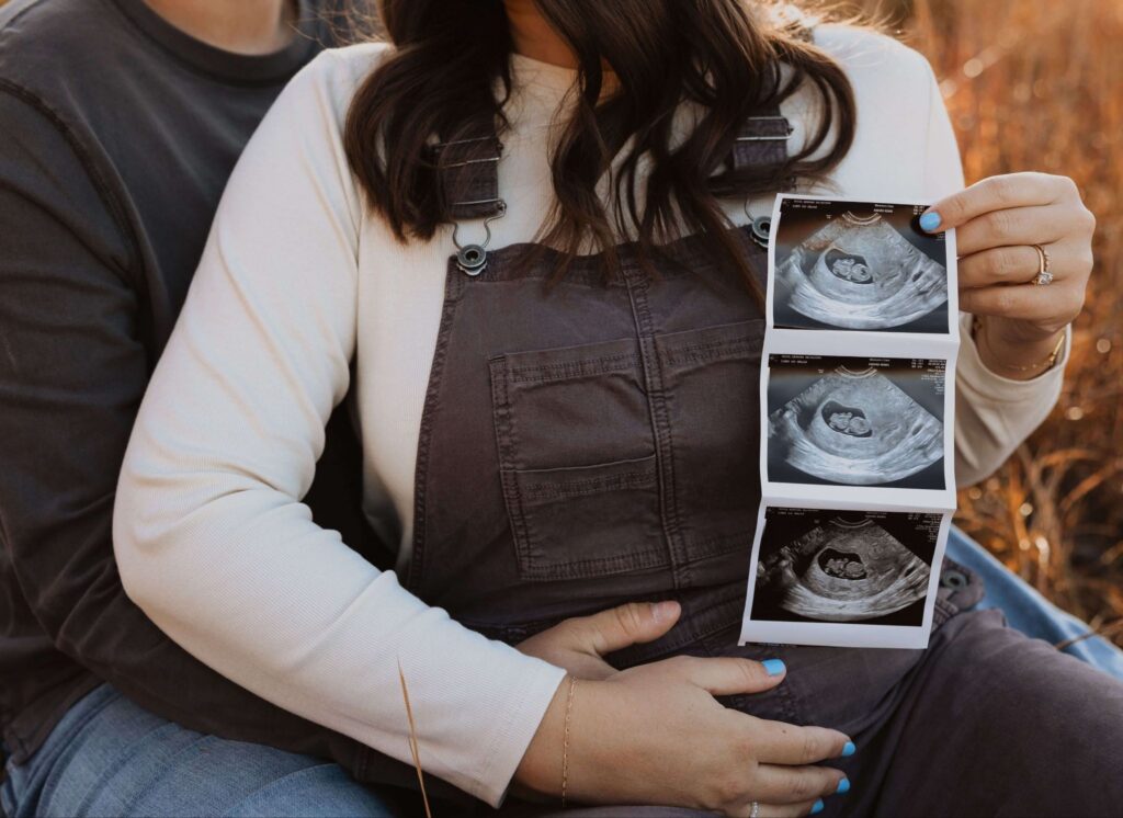 Man and woman holding sonogram for maternity photos in Kansas