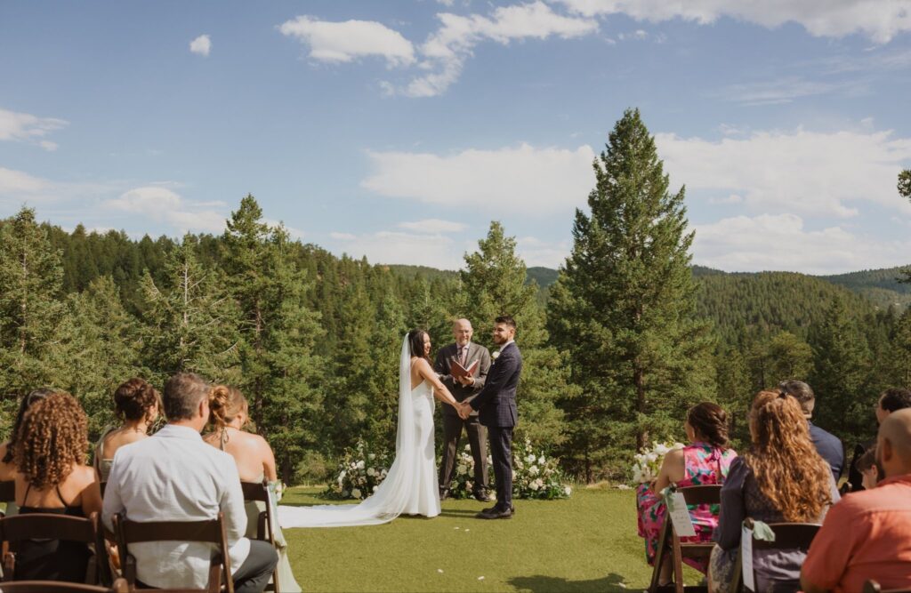 Bride and groom during a Steamboat Springs wedding ceremony surrounded by pine trees