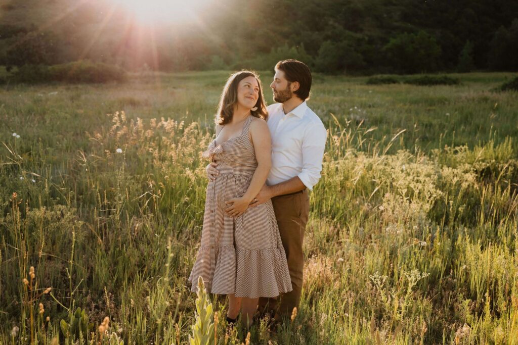 Man and pregnant woman posing in field for maternity photos in Kansas City